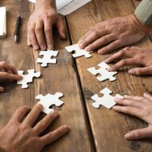 Multiple hands creating a jigsaw puzzle