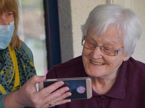 Older woman making video call with help of carer