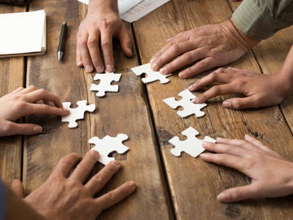 Multiple hands creating a jigsaw puzzle